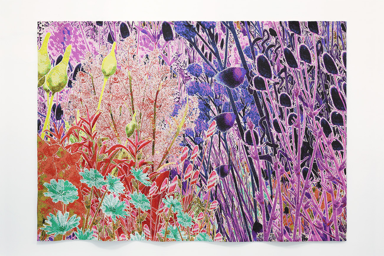 Vibrant coloured tapestry showing spring flowers in pinks, purples, yellows and reds with green by artist Alexandra Daisy Ginsberg, 2025