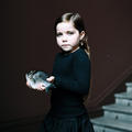 Tallulah and Jasmine, a photograph of a girl holding a fish against a black background with staircase on the right by artists Bettina von Zwehl, 2015