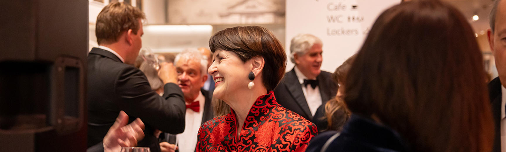 Trustee in a red dress in a group at a gala dinner 