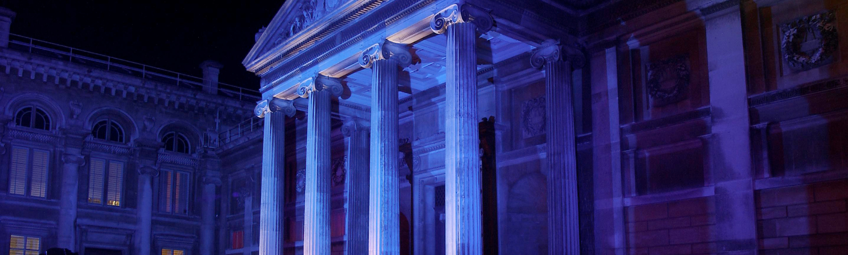 The Ashmolean Museum facade illuminated in pink and blue at night