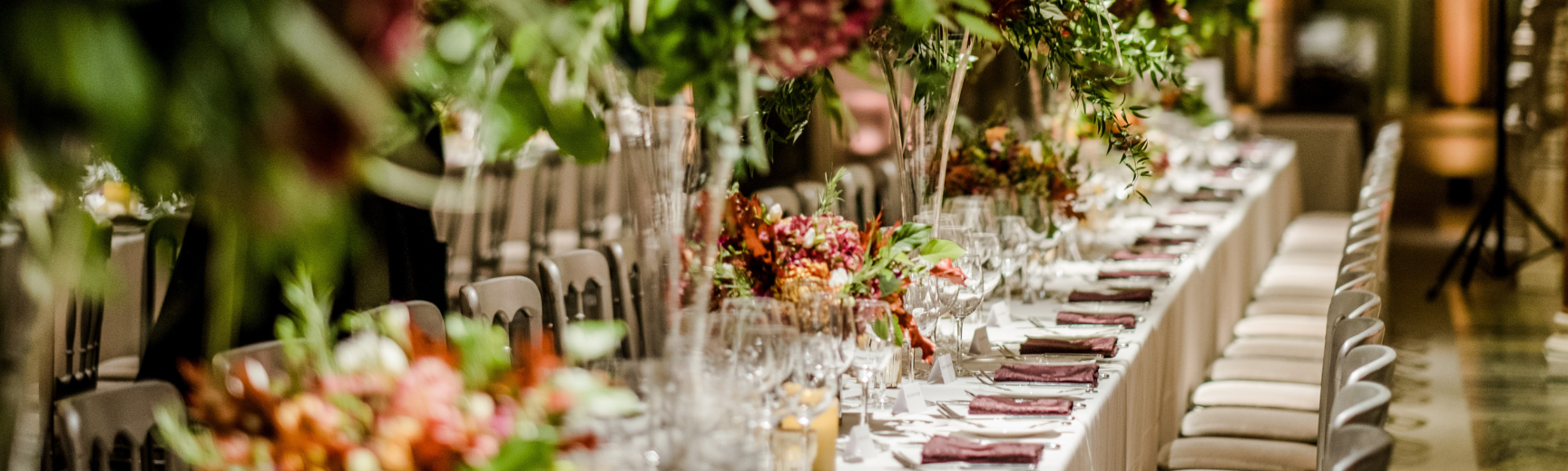 A table laid for a formal dinner fading into the distance with flowers running down the centre
