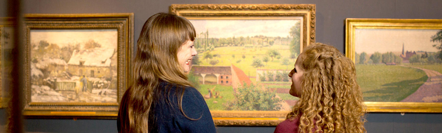 Two women looking at a Pissarro painting