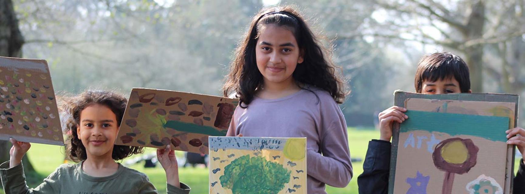 Children holding up their art at our Painting in the Park event in Oxford in March 2022