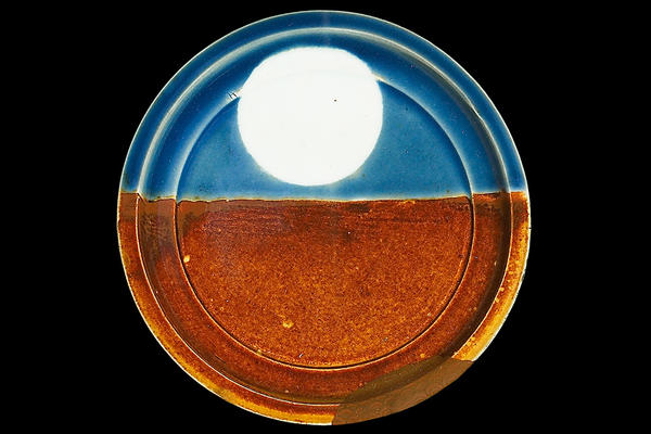 A round plate, the lower half orange, and the upper half blue with a large white circle in the centre