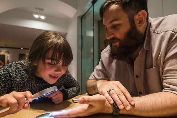 Child uses a magnifying glass to look closer at coins in the museum
