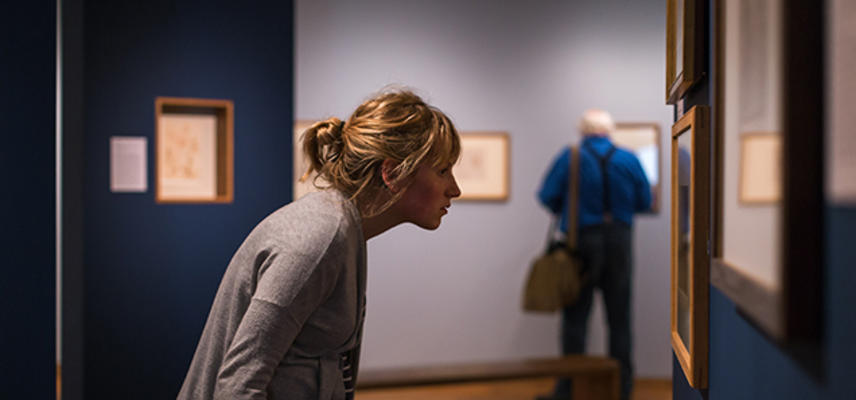 A woman looks at an artwork hanging on the wall of an art exhibition