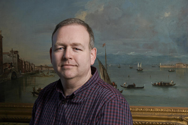 Conservator Jevon Thistlewood in front of an oil painting