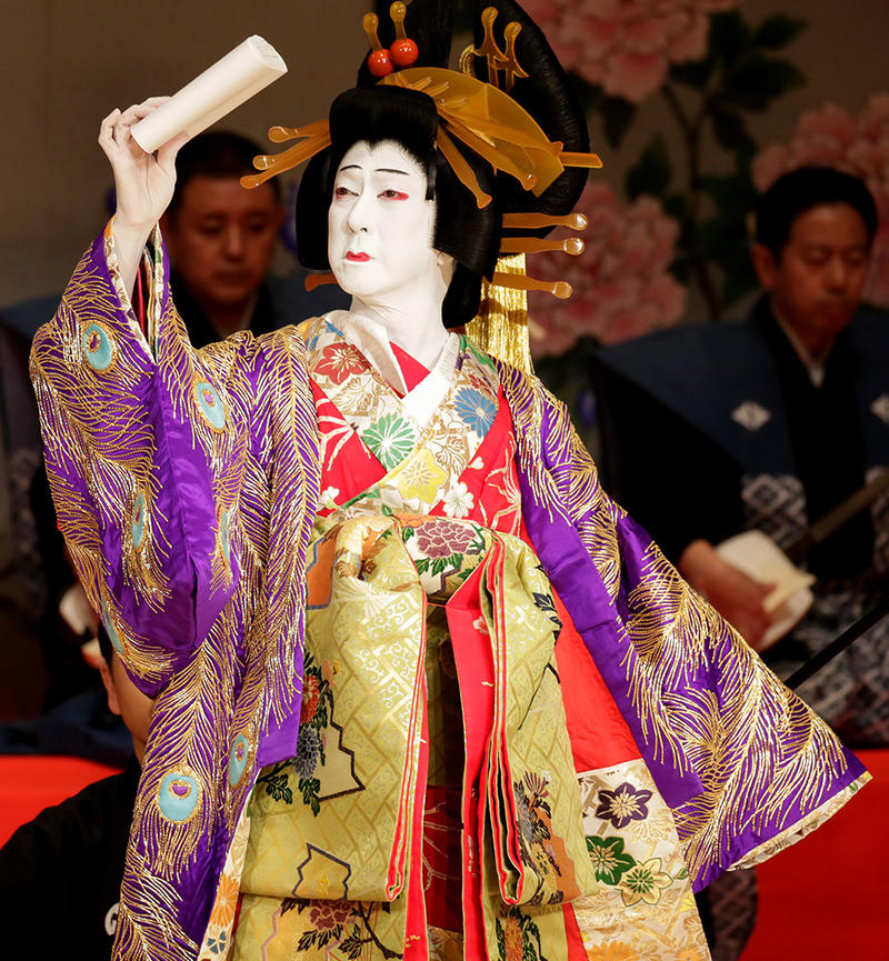 Kabuki performer in sumptuous costume with golds, peacock feathers and reds