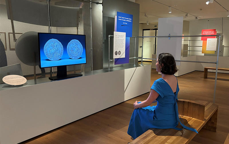 A visitor sitting looking at the new AI-generated Oxford Crown NFT on display in the Money Talks exhibition