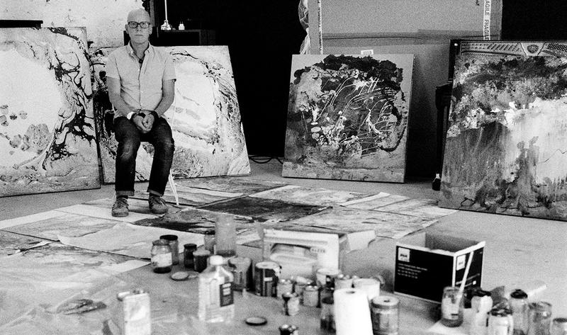 Black and white photo of Stanley Donwood in studio with artworks on the floor