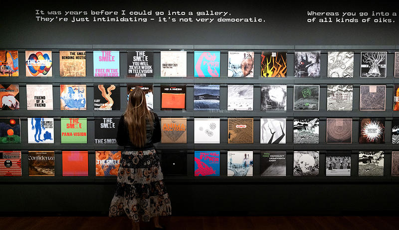 Visitor in the This Is What You Get exhibition looking at the large wall display of Radiohead and more albums