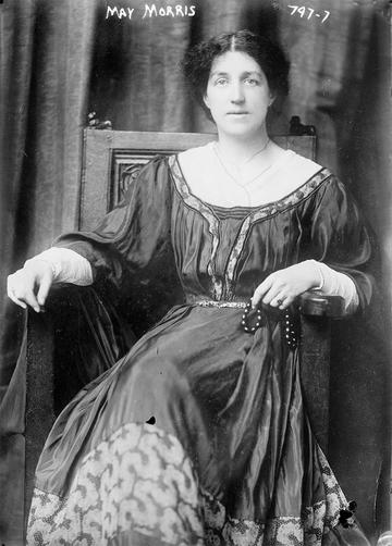 Black and white photo of May Morris sitting on a chair wearing a flowing dress, taken about 1909 for her American lecture tour 