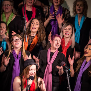 Choir singing wearing multi coloured scarves