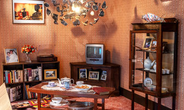 Shedding Light Caribbean living room display showing chandelier, photographs, tea set, china cabinet, tv, books and records