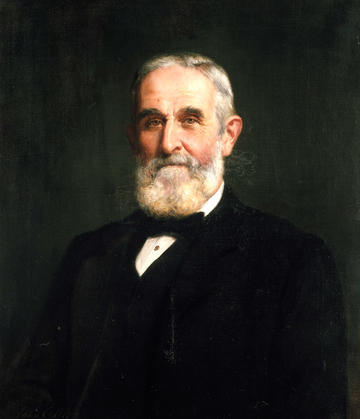 Sir John Evans wears a black suit and bow tie in this portrait in oil on canvas by John Collier, 1905