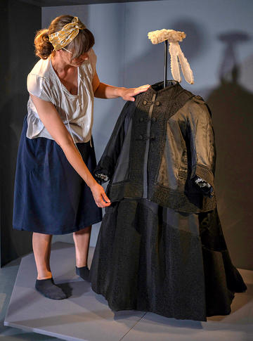 Queen Victoria's black mourning dress having a conservation check by one of our Conservation Team in the Colour Revolution exhibition gallery 